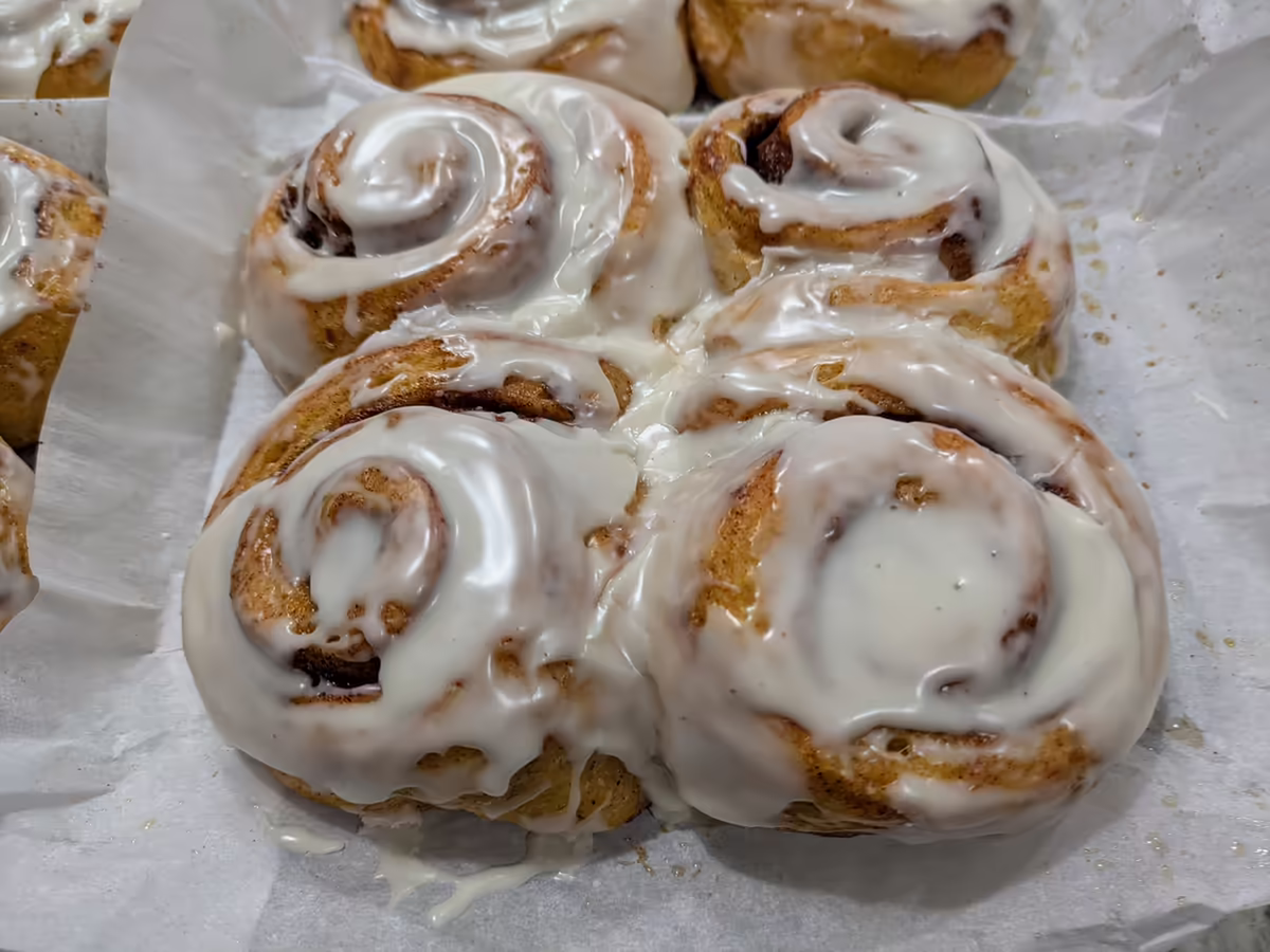 4 cinnamon rolls freshly glazed, on parchment paper