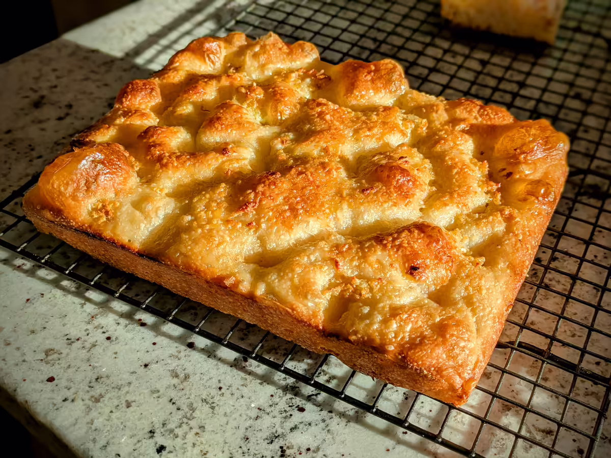 quarter-sheet garlic parmesan reggiano focaccia, on a cooling rack during golden hour