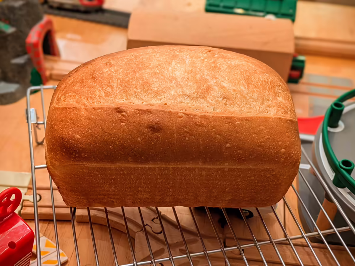 golden loaf of bread baked in loaf pan, with a nice rise and even score down the middle